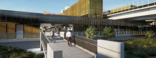 Modern urban infrastructure with a pedestrian bridge leading to a building labeled 'Hope Island.' Contemporary architecture with glass and metal facades, people walking and cycling, greenery and well-maintained landscaping.