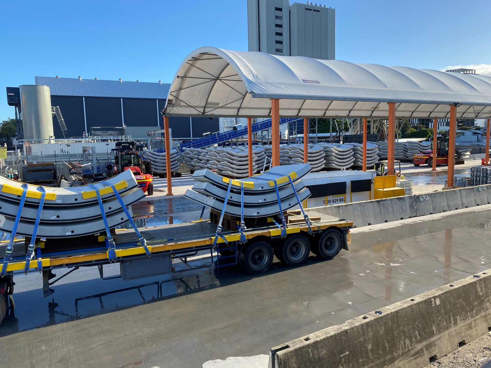 Piles of tunnel lining segments being transported on trucks.