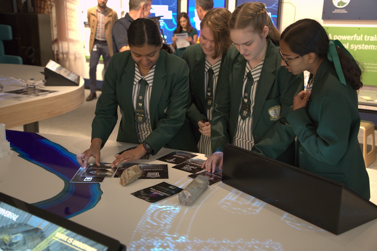 Students gather around educational activities on a table.